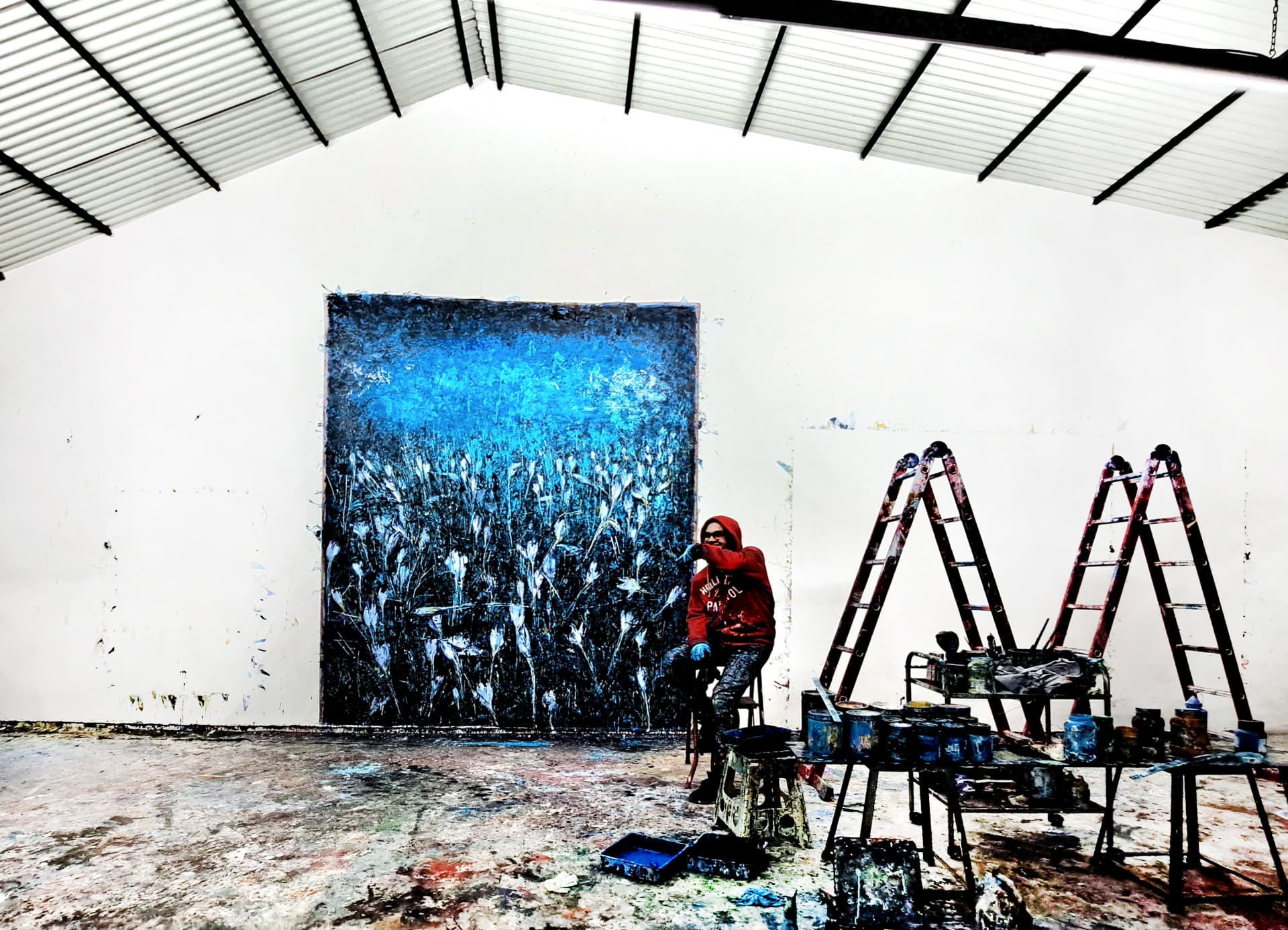 جلال‌الدین مشمولی در استودیو خود مقابل نقاشی امپاستوی آبی بزرگ | Jalaleddin Mashmooli in his studio before a large blue impasto painting