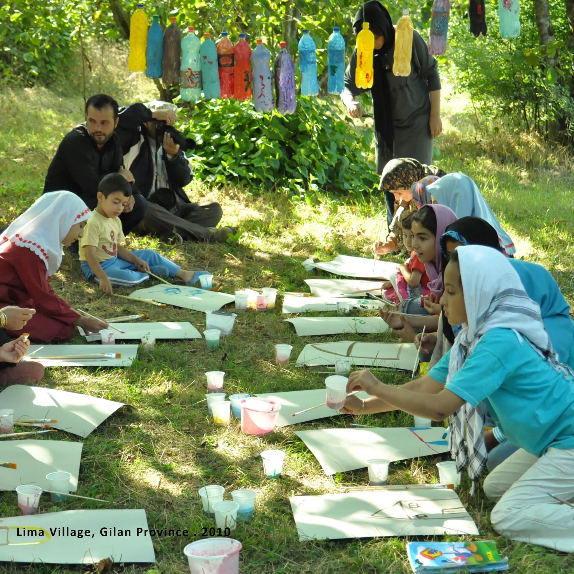 Community painting workshop with children and elders on the grass in Lima Village, Gilan Province